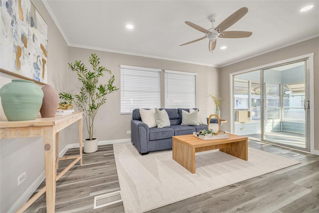 A living room features a blue sofa, wood coffee table, and sliding glass doors — 29250 US HIGHWAY 19 N UNIT 537, CLEARWATER, FL