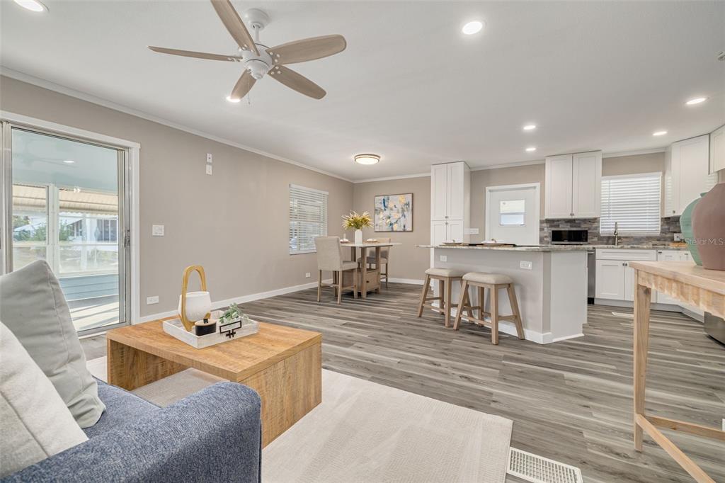 An open-concept living and dining area features light gray walls, wood-look flooring, and white cabinetry — 29250 US HIGHWAY 19 N UNIT 537, CLEARWATER, FL