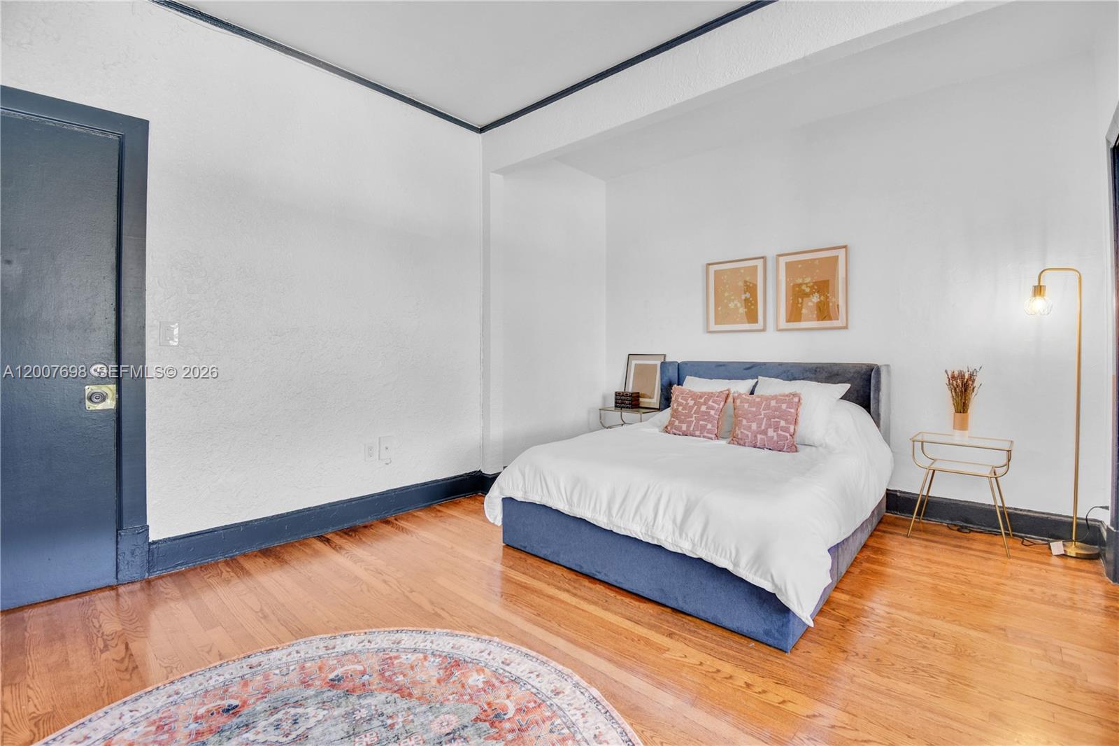 A bedroom features a blue upholstered bed, hardwood floors, and dark blue trim — 900 16th St # 201, Miami Beach FL 33139, MIAMI BEACH, FL