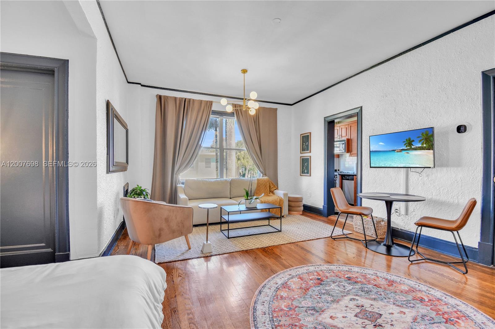 A living room features hardwood floors, a white sofa, a dining set, and dark trim — 900 16th St # 201, Miami Beach FL 33139, MIAMI BEACH, FL