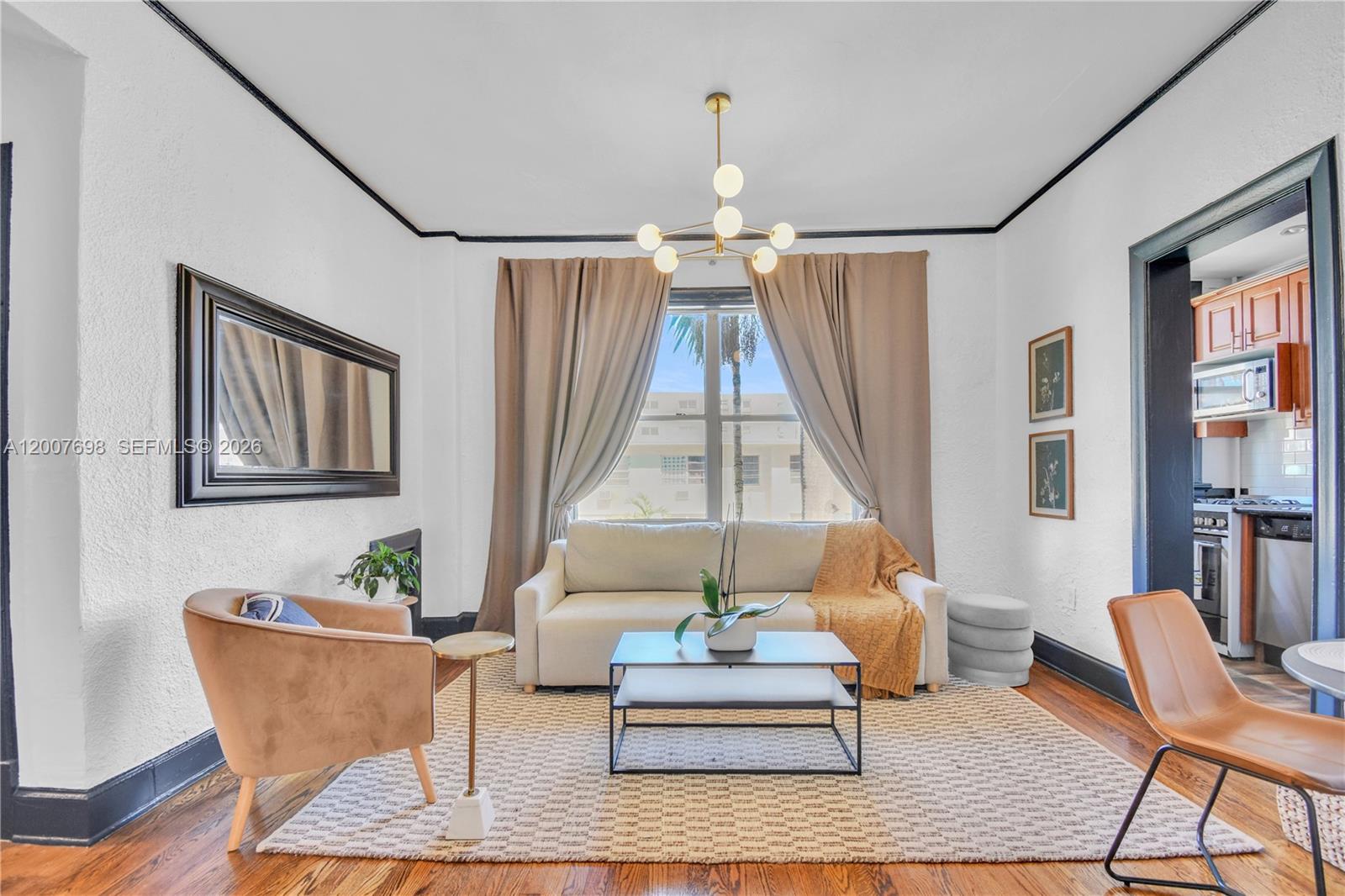 A living room features a sofa, coffee table, armchair, and a chandelier under white walls — 900 16th St # 201, Miami Beach FL 33139, MIAMI BEACH, FL