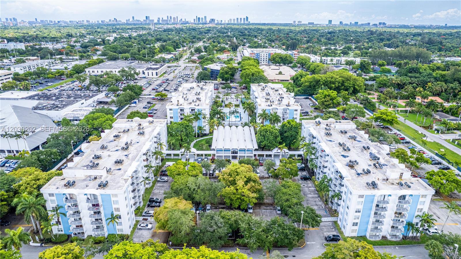 An aerial view shows multiple multi-story apartment buildings surrounded by parking lots and green trees — 482 NW 165th St Rd # 201, Miami FL 33169, MIAMI, FL