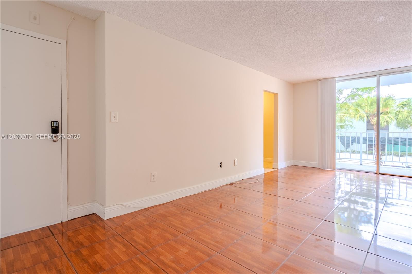 An empty room with glossy wood-look tile floors, a white door, and a sliding glass door — 482 NW 165th St Rd # 201, Miami FL 33169, MIAMI, FL