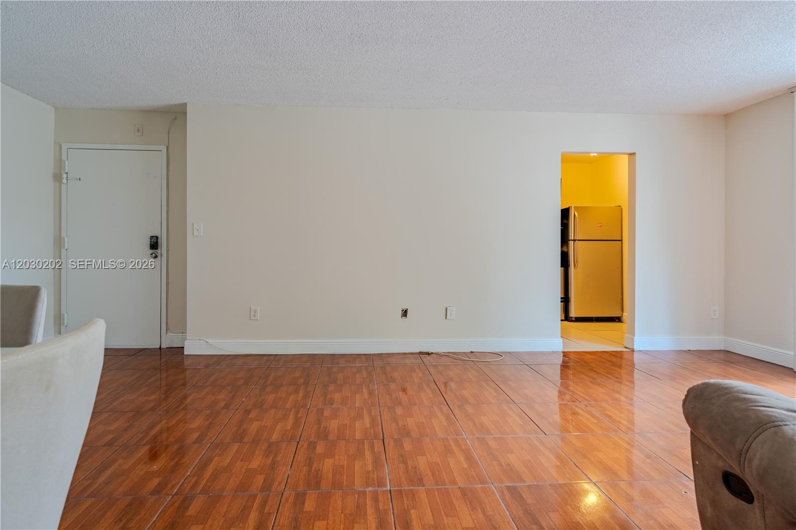A living room features beige walls, a popcorn ceiling, and glossy wood-look tile flooring — 482 NW 165th St Rd # 201, Miami FL 33169, MIAMI, FL