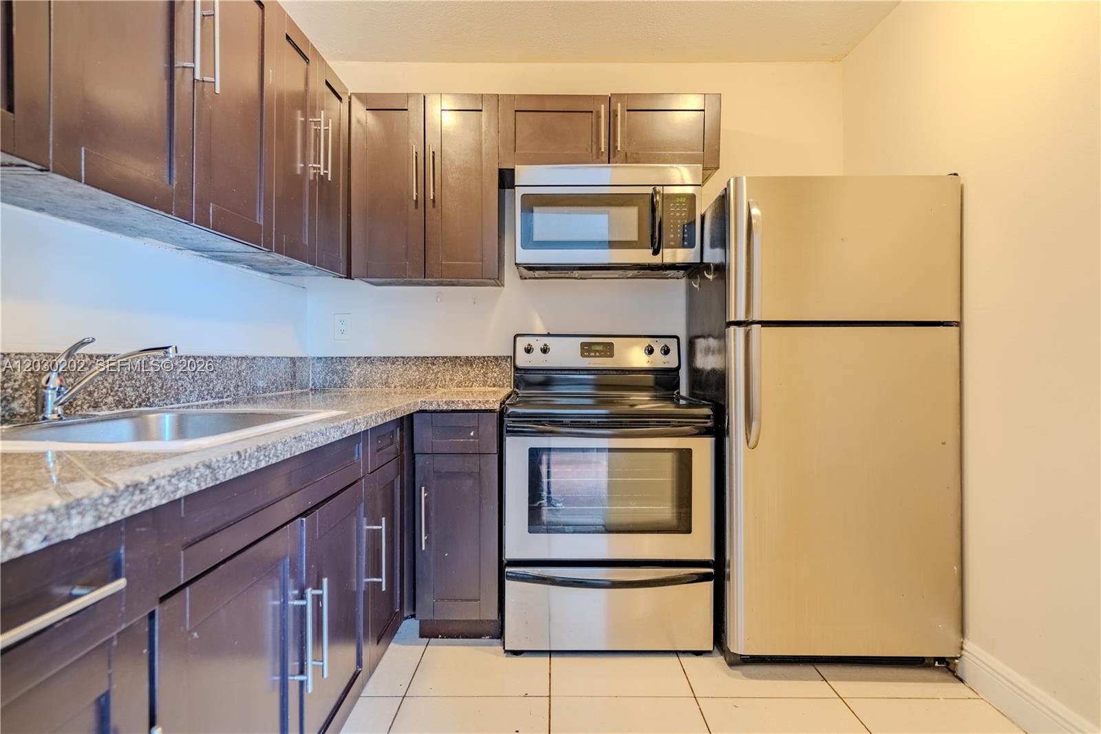 A kitchen features dark wood cabinets, stainless steel appliances, and granite countertops — 482 NW 165th St Rd # 201, Miami FL 33169, MIAMI, FL