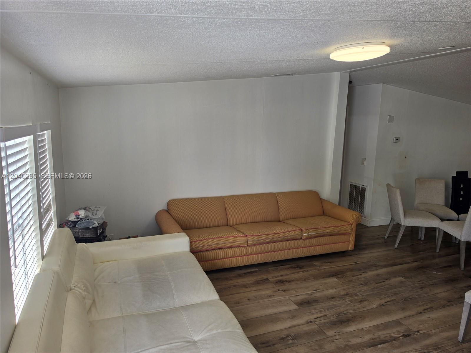 A living room features a white sofa, a striped tan sofa, and wood-look flooring — 1529 SW 131 Avenue, Miami FL 33184, MIAMI, FL