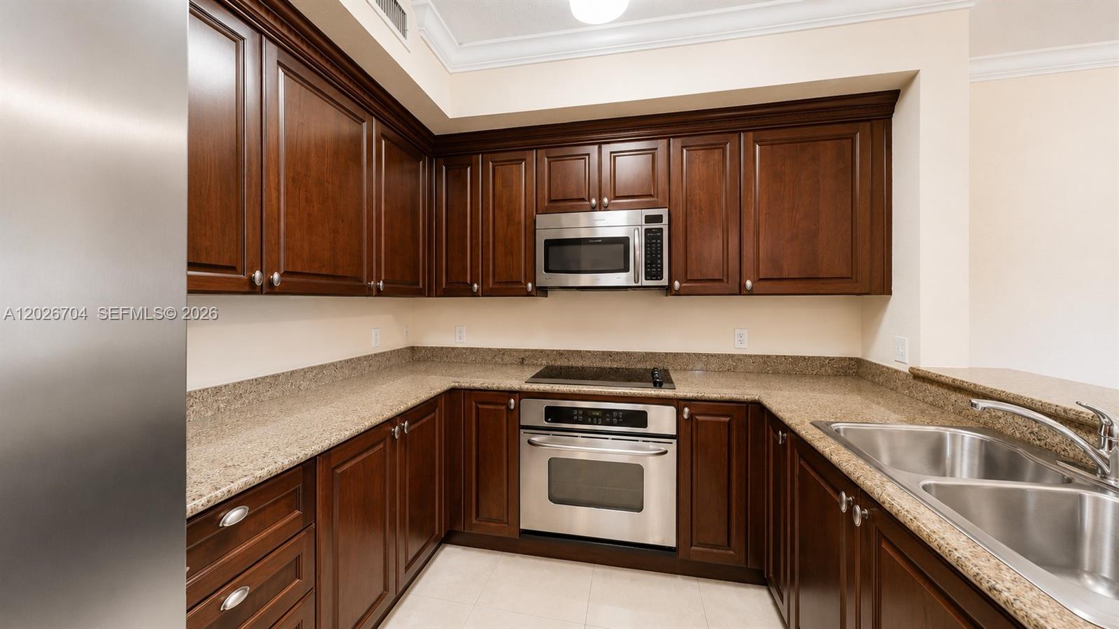 A kitchen features dark wood cabinets, granite countertops, and stainless steel appliances — 4106 Renaissance Way # 106, Boynton Beach FL 33426, BOYNTON BEACH, FL