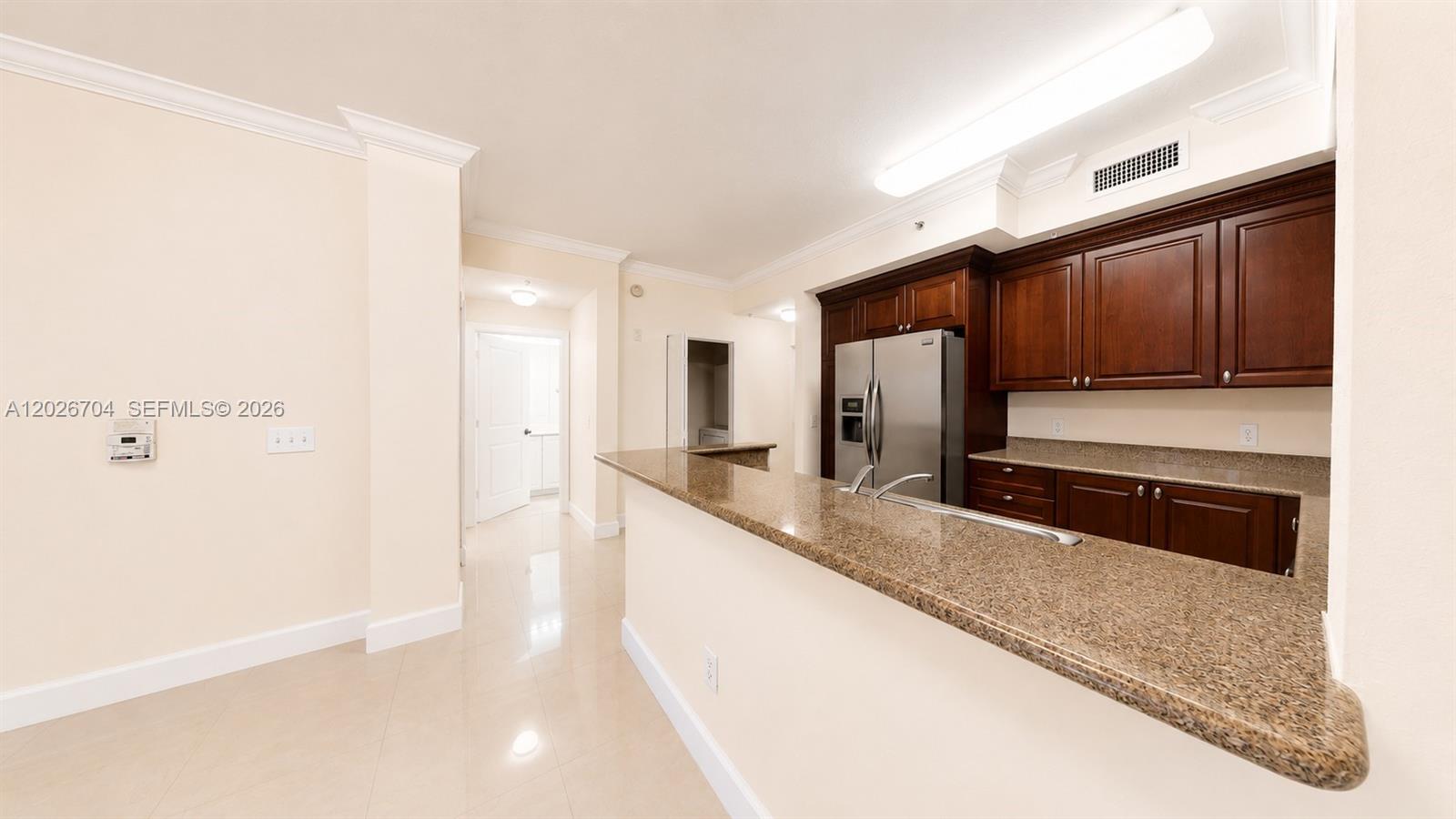 A kitchen features dark wood cabinets, granite countertops, stainless steel appliances, and tile flooring — 4106 Renaissance Way # 106, Boynton Beach FL 33426, BOYNTON BEACH, FL