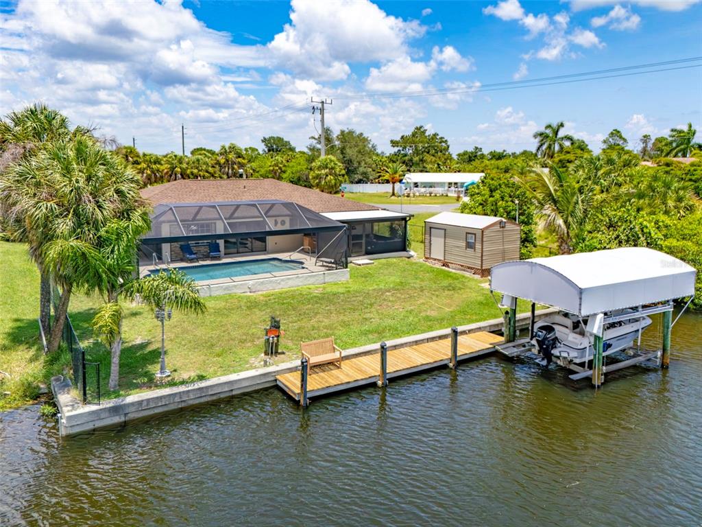 An aerial view of a waterfront house with a pool, dock, and boat lift — 18881 MCGRATH CIRCLE, PORT CHARLOTTE, FL