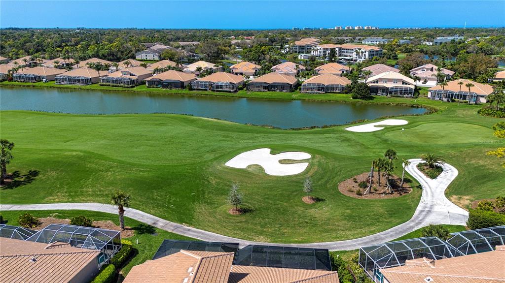 An aerial view shows a golf course fairway, a pond, and residential homes with pools — 9448 FOREST HILLS CIRCLE, SARASOTA, FL