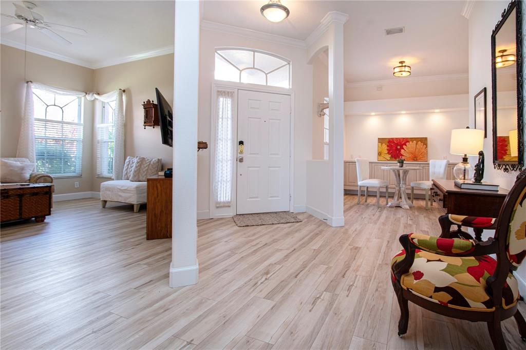 An entryway with light wood-look flooring leads to a living area and a dining nook — 9448 FOREST HILLS CIRCLE, SARASOTA, FL