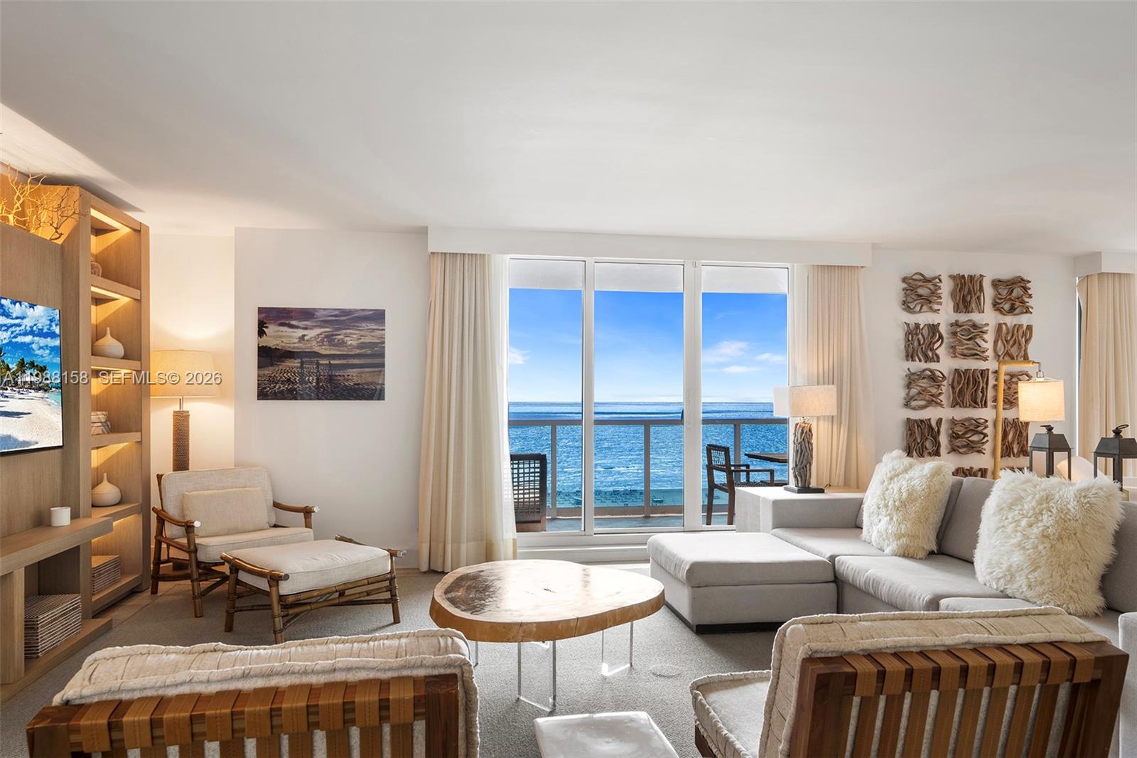 A living room features a sectional sofa, wooden coffee table, and ocean views through windows — 102 24th St # 1040, Miami Beach FL 33139, MIAMI BEACH, FL