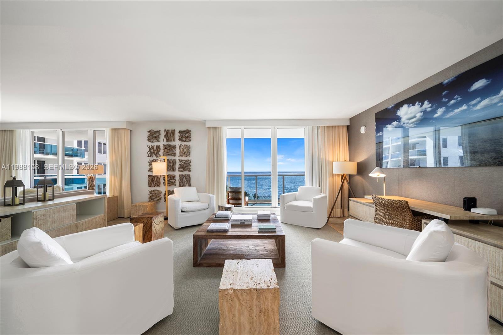 A living room features white armchairs, a wooden coffee table, and a view of the ocean — 102 24th St # 1040, Miami Beach FL 33139, MIAMI BEACH, FL