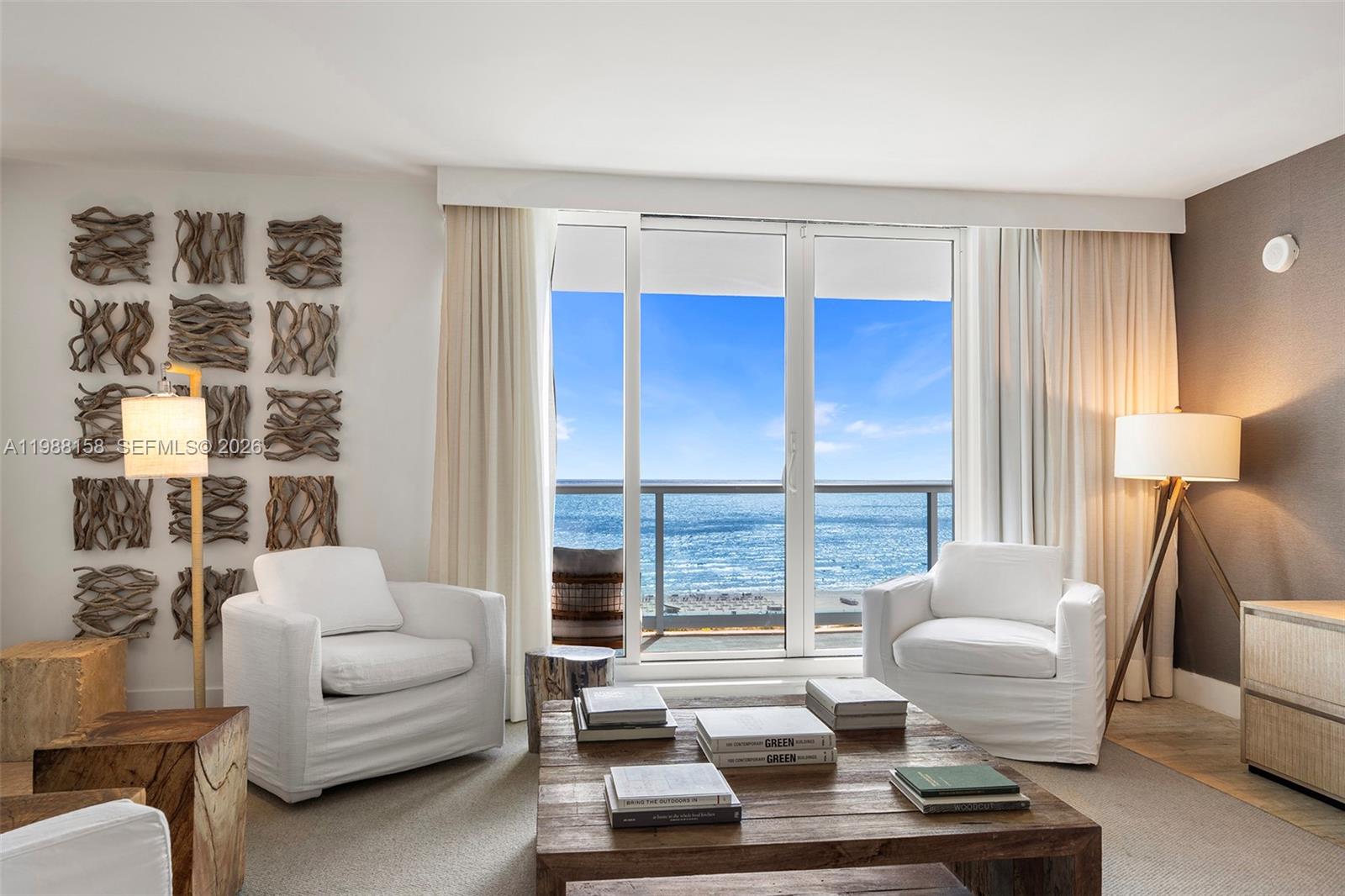 A living room features two white armchairs, a wooden coffee table, and ocean views — 102 24th St # 1040, Miami Beach FL 33139, MIAMI BEACH, FL