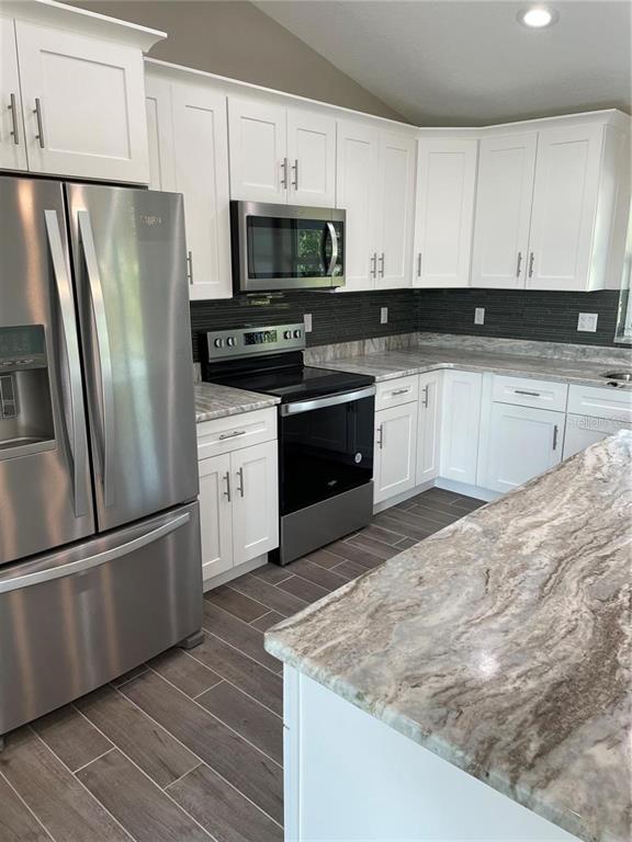 A kitchen features white cabinets, stainless steel appliances, and patterned stone countertops — 00 LONGFELLOW LANE, NORTH PORT, FL