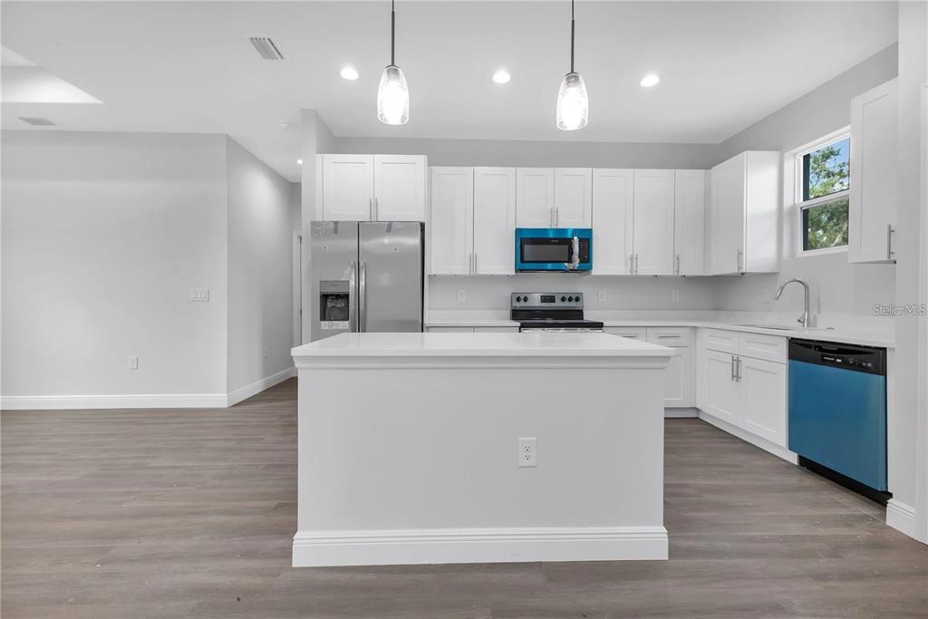 A modern kitchen features white cabinetry, stainless steel appliances, a center island, and wood-look flooring — 00 LONGFELLOW LANE, NORTH PORT, FL