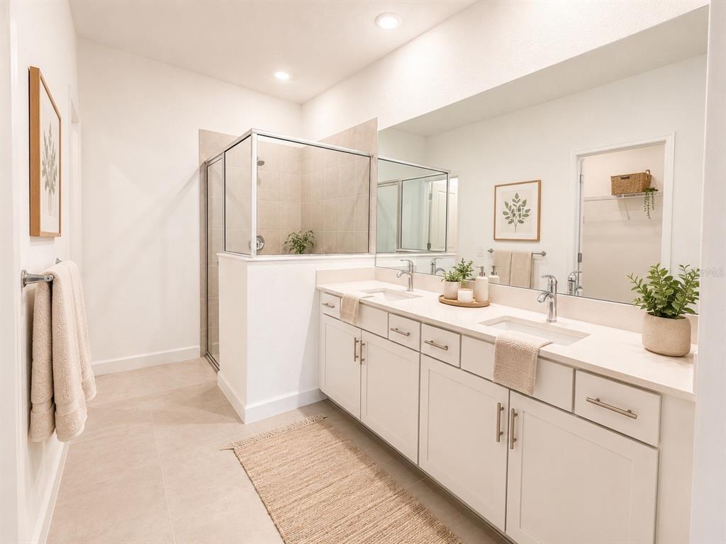 A bright bathroom features a double vanity with white cabinets, a large mirror, and a shower — 8206 SAINT KITTS CIRCLE, ENGLEWOOD, FL