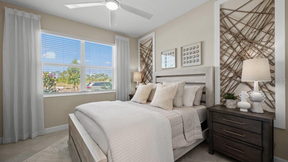 A bedroom features a light-colored bed, two nightstands with lamps, and rope wall art — 8206 SAINT KITTS CIRCLE, ENGLEWOOD, FL