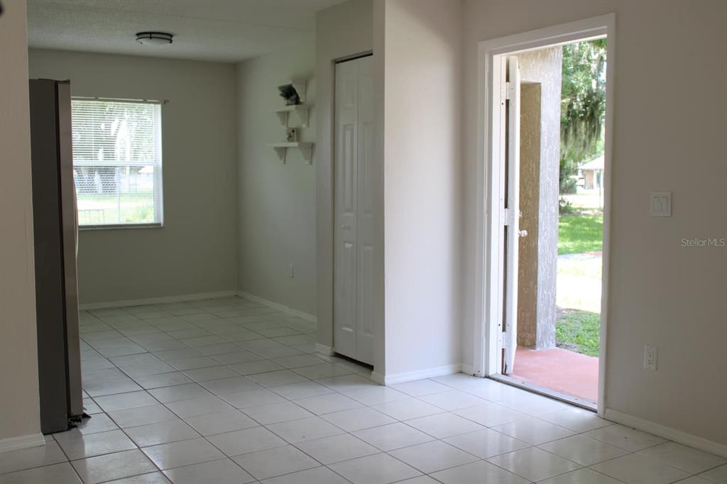 A tiled kitchen area features a white door, a closet, and an open exterior doorway — 703 MICHIGAN COURT UNIT 2, ST CLOUD, FL