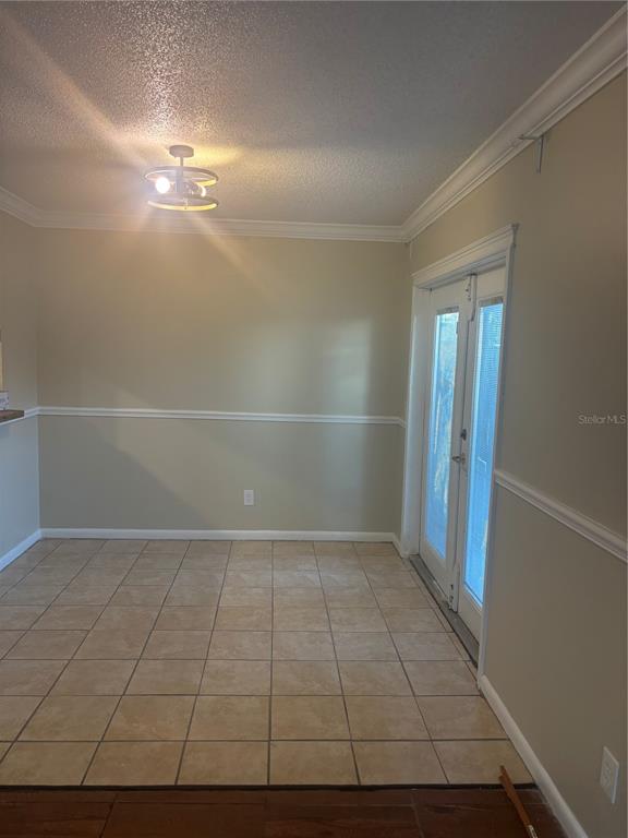 A dining area with beige walls, chair rail molding, tile flooring, and French doors — 1320 MOUNTAINVIEW UNIT 1320, TAMPA, FL