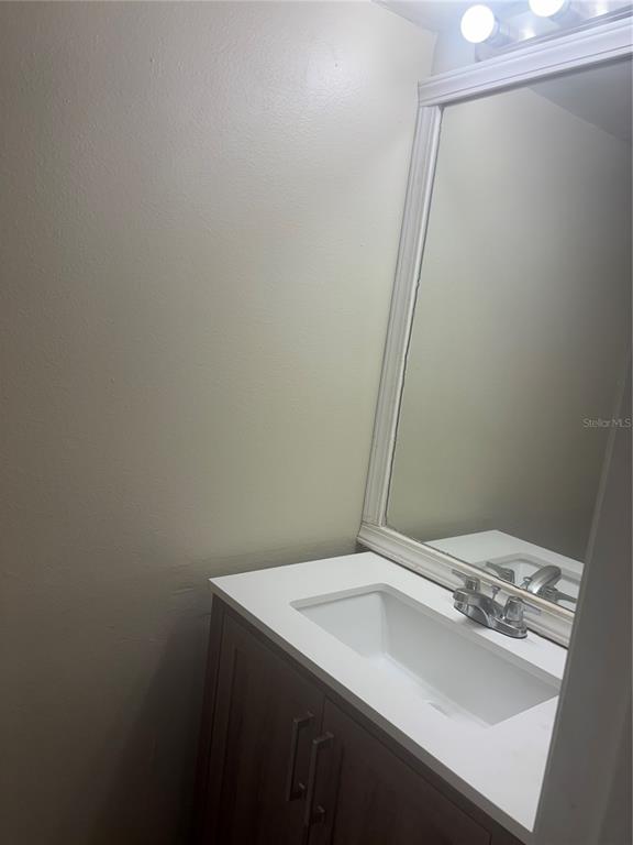 A bathroom vanity with a white countertop, rectangular sink, and a framed mirror — 1320 MOUNTAINVIEW UNIT 1320, TAMPA, FL