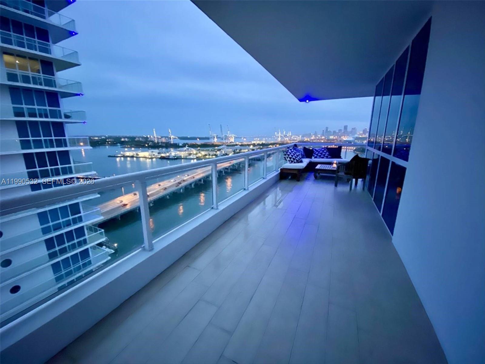A high-rise balcony features wood-look flooring, outdoor seating, and a view of a city skyline — 540 West Ave # 2011, Miami Beach FL 33139, MIAMI BEACH, FL