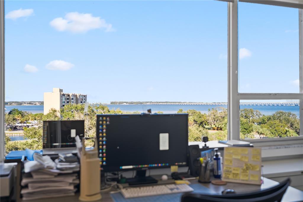 A home office desk faces a large window with a view of the water and bridge — 2621 COVE CAY DRIVE UNIT 804, CLEARWATER, FL