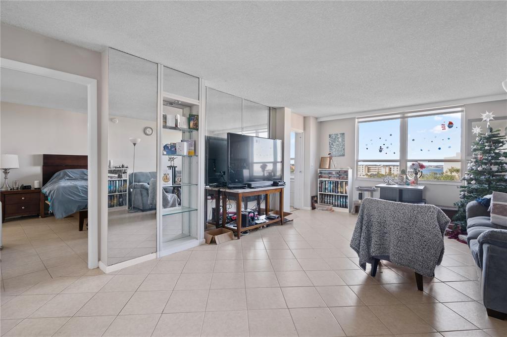 A living room features tiled floors, mirrored walls, a television console, and a view of water — 2621 COVE CAY DRIVE UNIT 804, CLEARWATER, FL