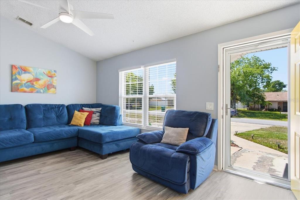 A living room features a blue sectional sofa, a matching recliner, and a glass door — 2632 DERBY DRIVE, DELTONA, FL