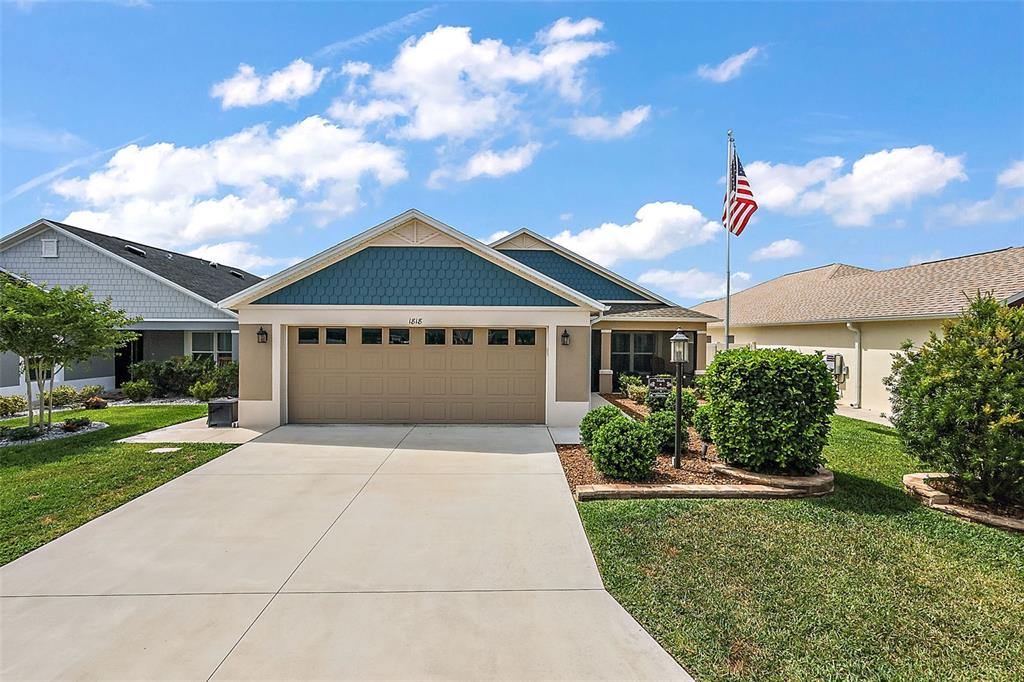 A single-story house with a tan garage, blue shingle siding, and a front yard lawn — 1818 TRIMARCHE TERRACE, THE VILLAGES, FL