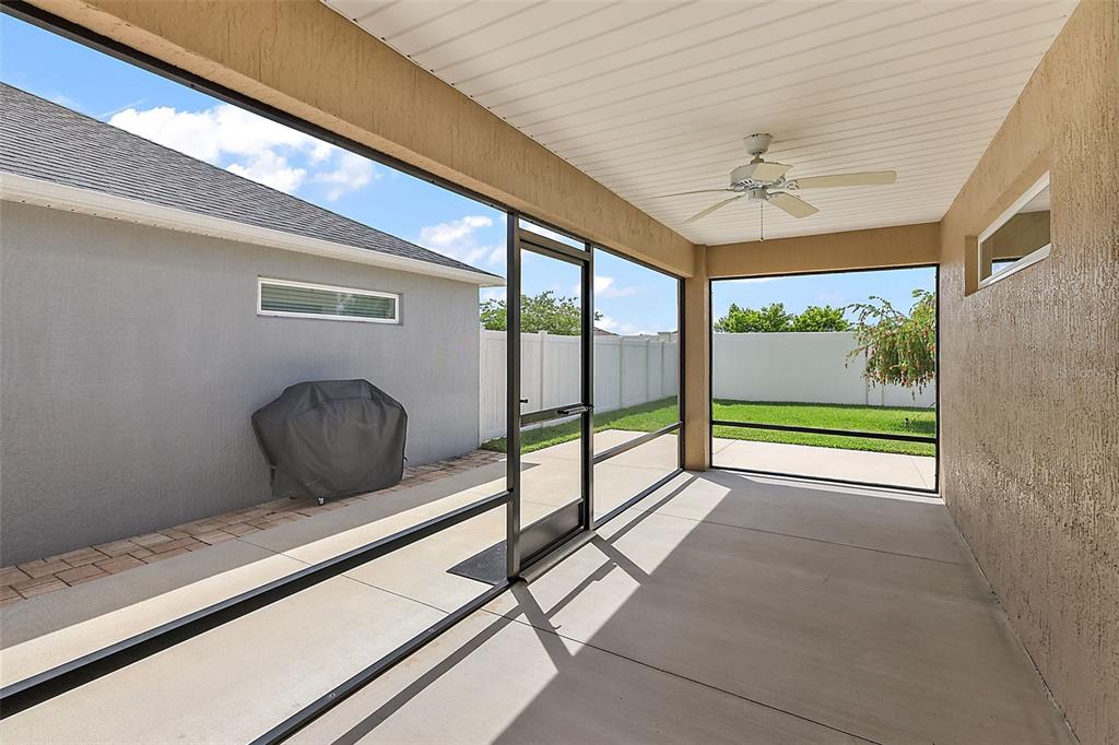 A covered, screened-in patio features a concrete floor, a ceiling fan, and a grill cover — 1818 TRIMARCHE TERRACE, THE VILLAGES, FL