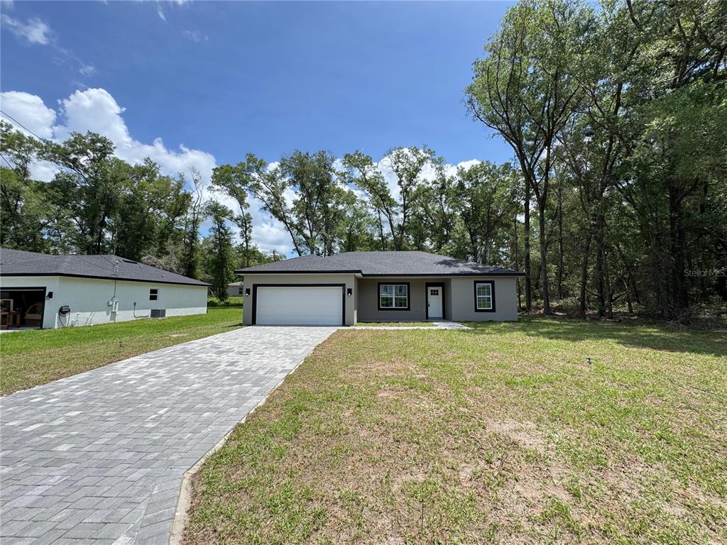 A single-story house with a gray exterior, a paved driveway, and a two-car garage — 7751 N CREEK WAY, CITRUS SPRINGS, FL