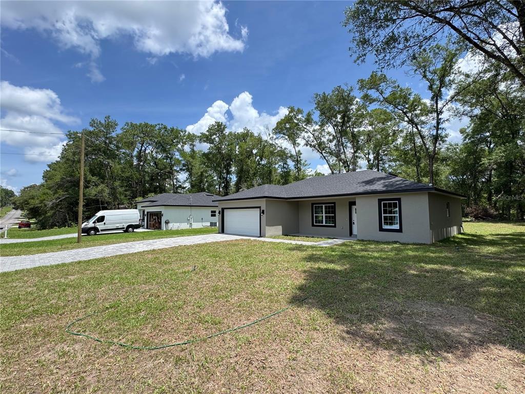 A single-story house with a gray exterior, dark roof, and attached garage sits on a lawn — 7751 N CREEK WAY, CITRUS SPRINGS, FL