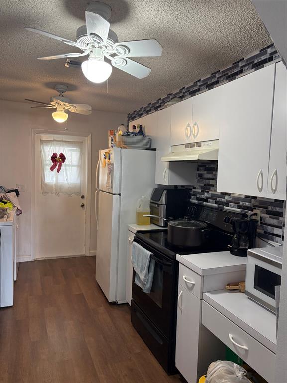 A kitchen features white cabinets, a black stove, a refrigerator, and two ceiling fans — 60 WINTER RIDGE ROAD UNIT 60, WINTER HAVEN, FL