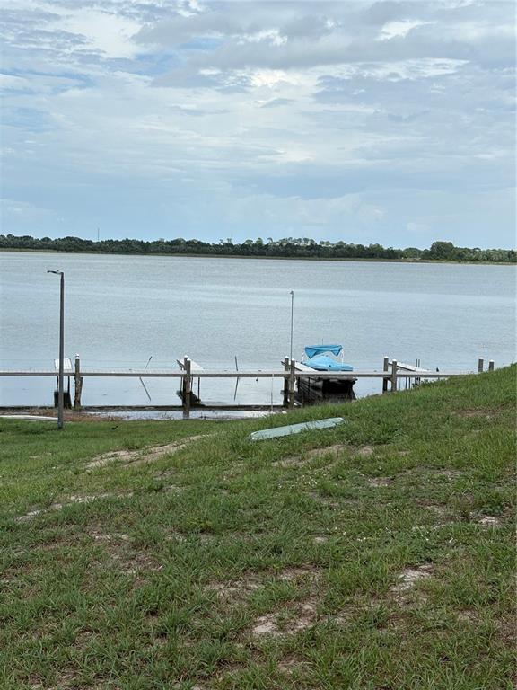 A grassy slope leads down to a wooden dock with a boat on a lake — 60 WINTER RIDGE ROAD UNIT 60, WINTER HAVEN, FL