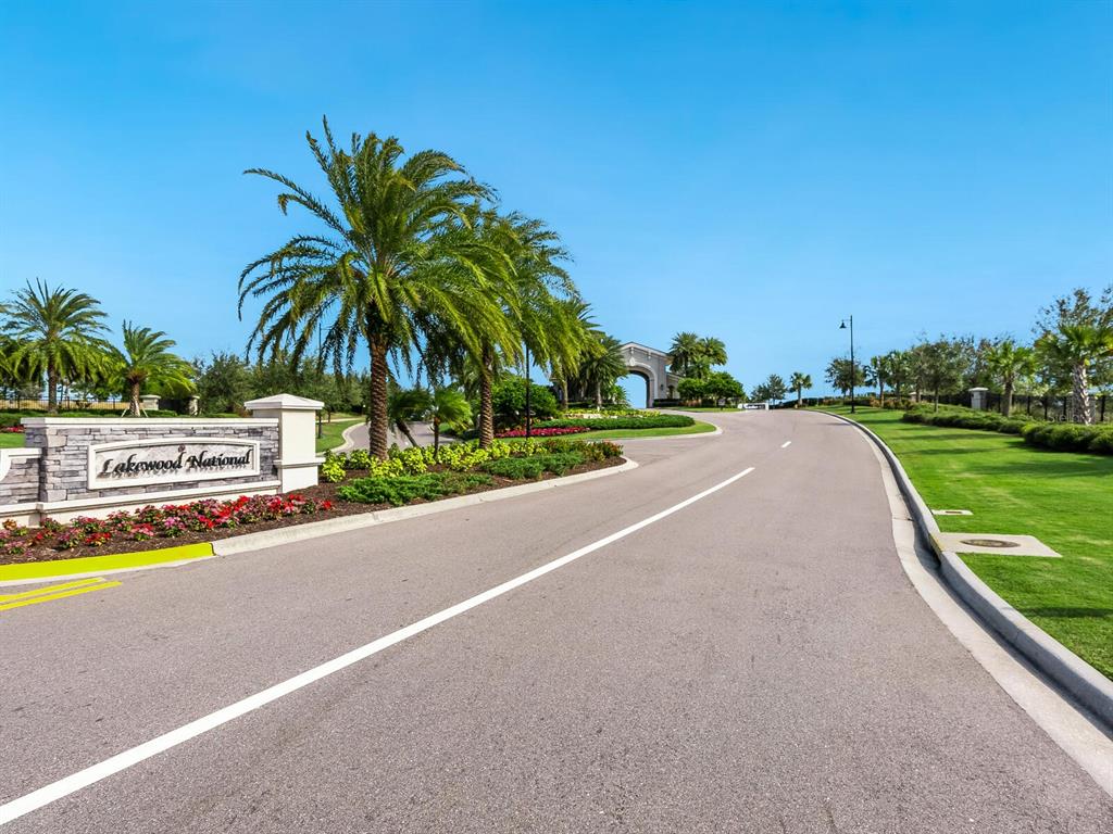 A paved road leads toward the gated entrance of the Lakewood National residential community — 17006 VARDON TERRACE UNIT 402, BRADENTON, FL