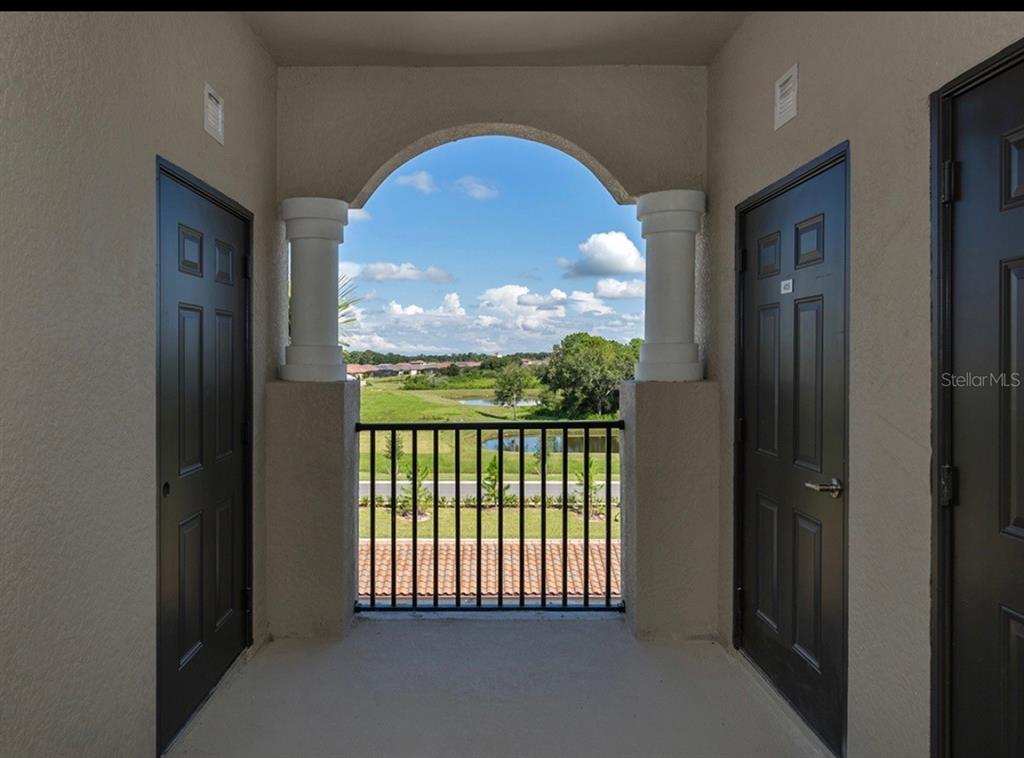 An arched balcony overlooking a grassy landscape with a pond and a blue sky — 17006 VARDON TERRACE UNIT 402, BRADENTON, FL