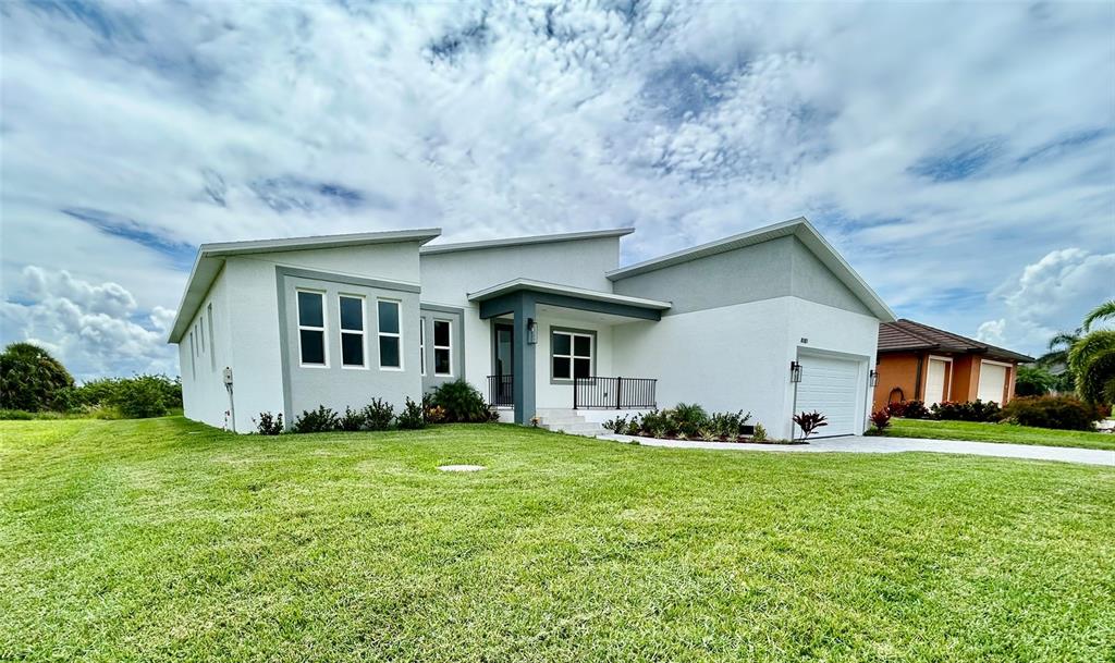 A modern, single-story white house with a gray roof and a front-facing garage — 8181 TECUMSEH CIRCLE, PORT CHARLOTTE, FL