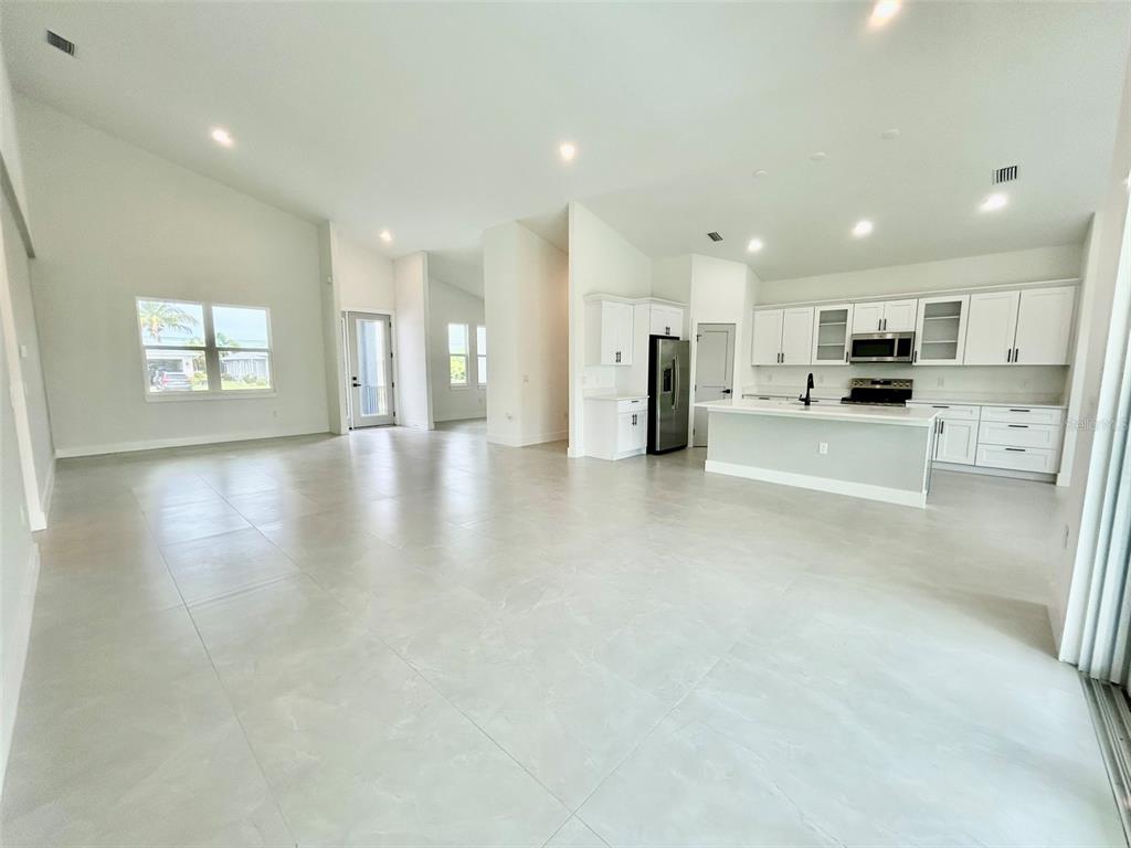 An open-concept living area features white cabinetry, a kitchen island, and light-colored tile flooring — 8181 TECUMSEH CIRCLE, PORT CHARLOTTE, FL