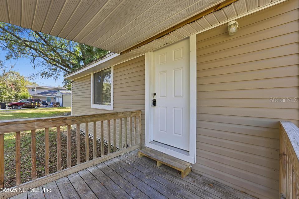 A wooden porch with a railing leads to a white door on a beige-sided house — 3428 GLEN STREET, JACKSONVILLE, FL