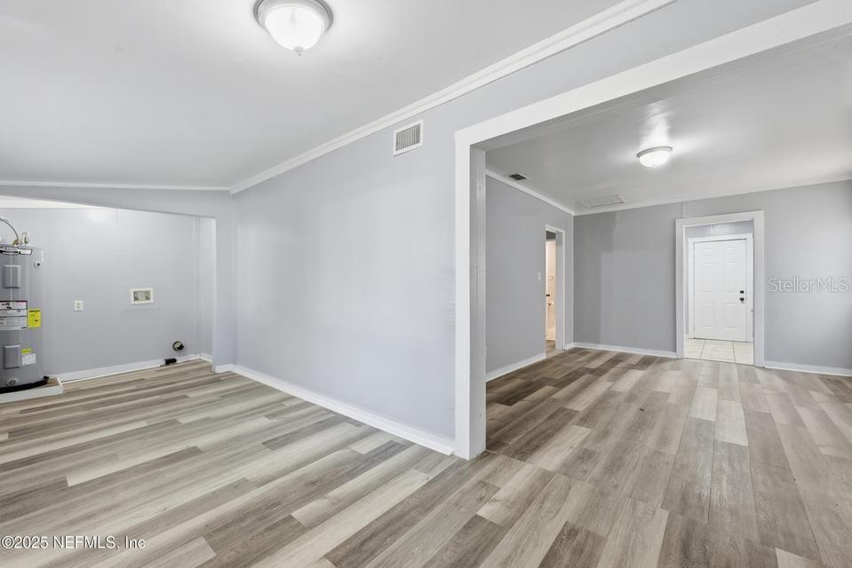 An interior view shows a room with light gray walls, wood-look flooring, and an open doorway — 3428 GLEN STREET, JACKSONVILLE, FL