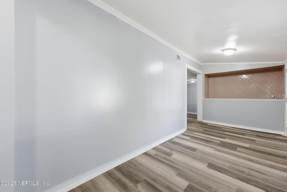 An empty room features light gray walls, wood-look flooring, and a recessed tiled wall niche — 3428 GLEN STREET, JACKSONVILLE, FL