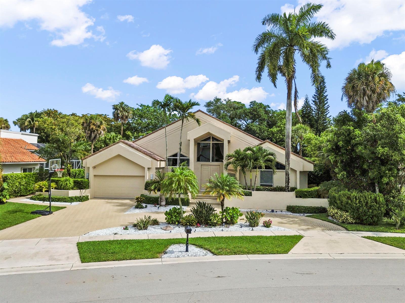 A tan, single-story house with a paved driveway, palm trees, and a basketball hoop — 7165 Mariana Court, Boca Raton FL 33433, BOCA RATON, FL