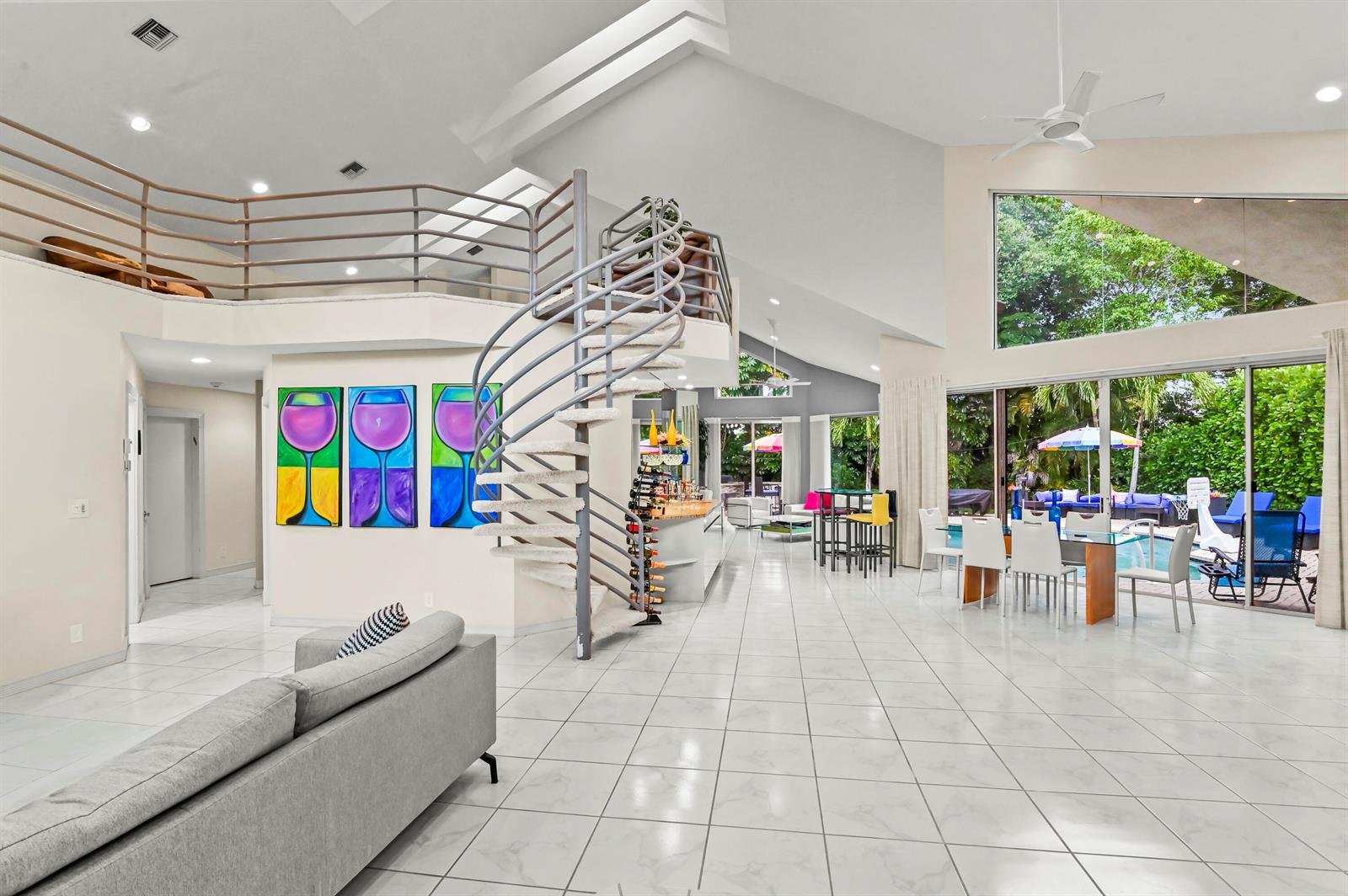 A spacious living area features a spiral staircase, tile flooring, and large windows overlooking a pool — 7165 Mariana Court, Boca Raton FL 33433, BOCA RATON, FL