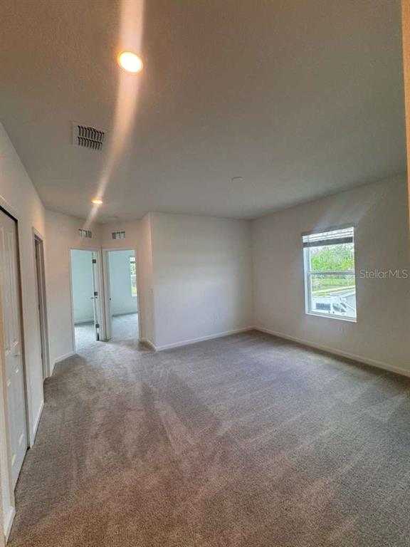 An empty bedroom with beige carpet, white walls, recessed lighting, and a window — 3060 CHROMATIC STREET, KISSIMMEE, FL