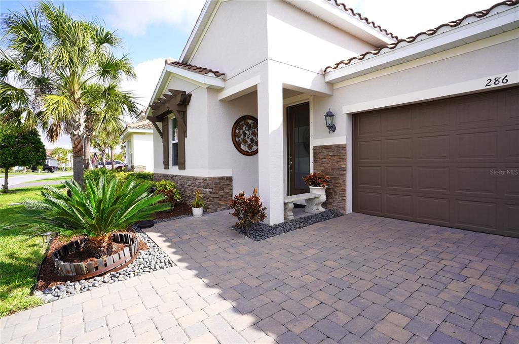 The exterior of a house features a paved driveway, a garage, and a palm tree — 286 DAYLILY BOULEVARD, NOKOMIS, FL