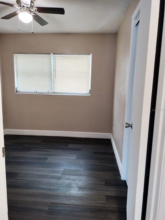 A bedroom with dark wood-look flooring, beige walls, a ceiling fan, and a window — 3246 NE 7TH LANE, OCALA, FL