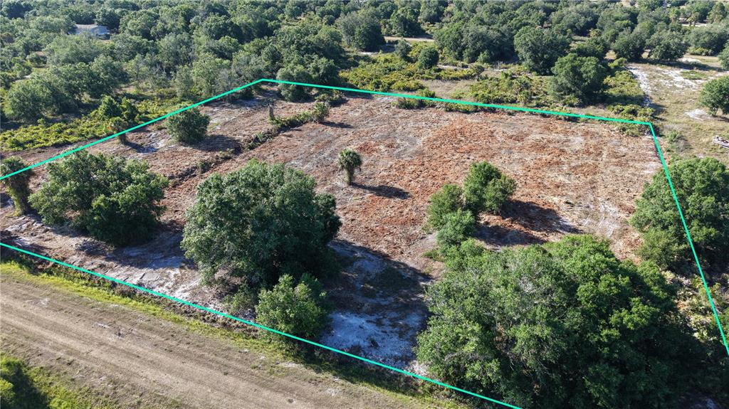 An aerial view shows a cleared, rectangular plot of land surrounded by trees and vegetation — 17017 NW 262ND STREET, OKEECHOBEE, FL