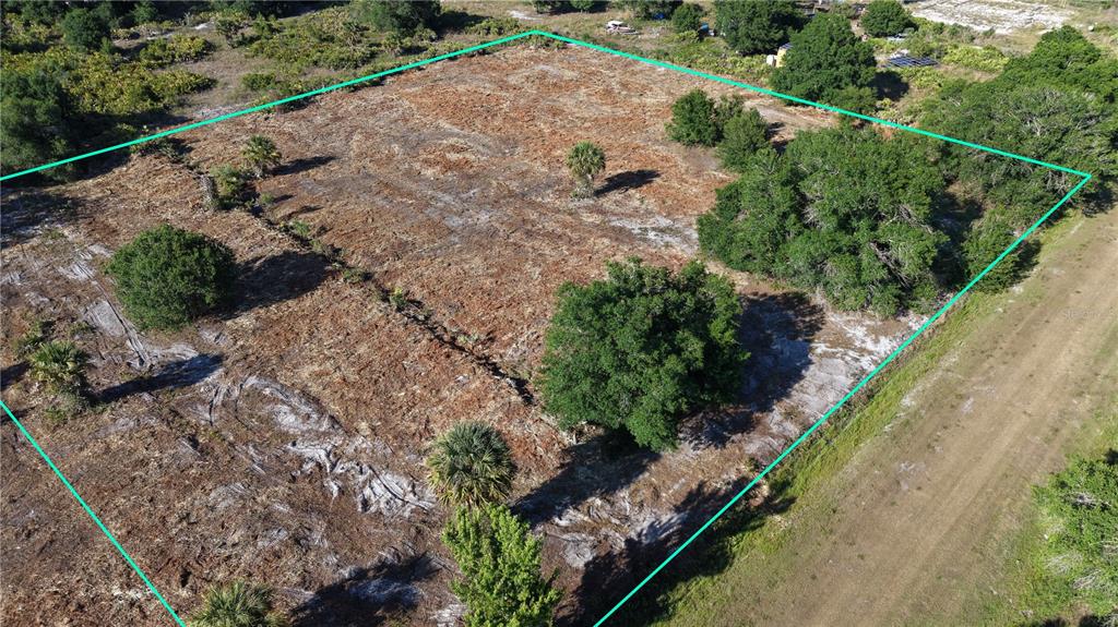 An aerial view shows a cleared, rectangular plot of land outlined in teal — 17017 NW 262ND STREET, OKEECHOBEE, FL