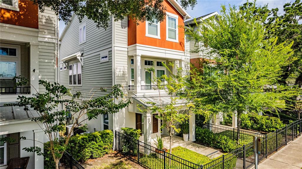 A three-story house with light siding and an orange upper facade sits behind a fence — 858 N THORNTON AVENUE, ORLANDO, FL